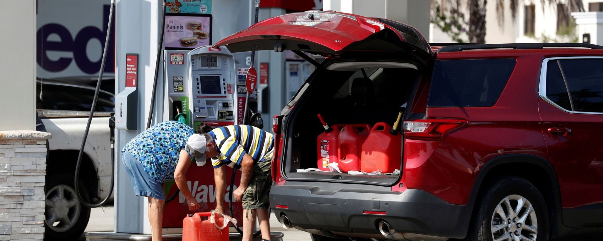 A couple fills up multiple 5 gallon gas tanks at a Wawa gas station, after a cyberattack crippled the biggest fuel pipeline in the country, run by Colonial Pipeline, in Tampa, Florida, U.S., May 12, 2021. - Sputnik International, 1920, 08.03.2022