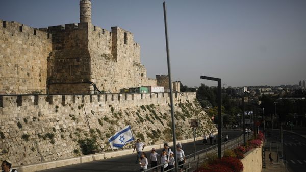 Youths wave an Israeli flag during a parade marking Jerusalem Day, amid Israeli-Palestinian tension, as they walk near the wall surrounding Jerusalem's Old City May 10, 2021. May 10, 2021. - Sputnik International