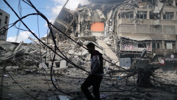A Palestinian man walks past the remains of a tower building which was destroyed in Israeli air strikes, amid a flare-up of Israeli-Palestinian violence, on the first day of the Eid al-Fitr holiday in Gaza City, 13 May 2021 - Sputnik International