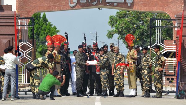 Indian Border Security Force (BSF) commandant Sudeep (centre R) presents sweets to Pakistani Wing Commander Bilal (centre L) on the occasion of the Eid al-Adha festival at the India-Pakistan Wagah border post on September 2, 2017 - Sputnik International