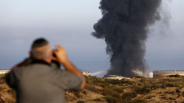 An Israeli man watches from a distance as smoke billows early on May 12, 2021 from Ashkelon's refinery, hit by Hamas rockets the previous day, in the southern Israeli city, near the Gaza Strip - Sputnik International