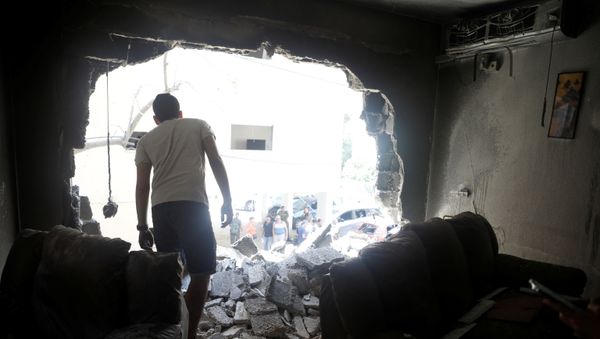 A man stands atop rubble as he surveys the damage after a rocket launched overnight from the Gaza Strip hit a residential building in Petah Tikva, Israel May 13, 2021 - Sputnik International