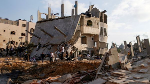 Palestinians gather around the ruins of buildings destroyed in Israeli airstrikes amid a flare-up of Israeli-Palestinian violence, in the northern Gaza Strip on 13 May 2021. - Sputnik International