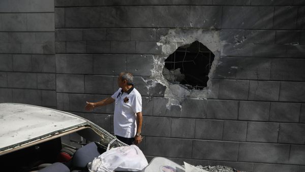 A man inspects the damaged wall of a residential building that was hit by a rocket fired from the Gaza Strip in Ashkelon, Israel, Friday, May 14, 2021.  - Sputnik International