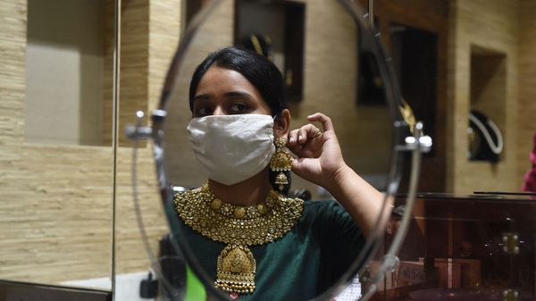 A customer wearing a face mask as a preventive measure against the COVID-19 coronavirus, looks herself in the mirror while trying on gold jewelry in an Ahmedabad shop on July 31, 2020. A customer wearing a face mask as a preventive measure against the COVID-19 coronavirus, looks herself in the mirror while trying on gold jewelry in an Ahmedabad shop on July 31, 2020. - Sputnik International