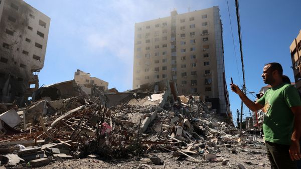 A Palestinian man takes a photograph with his mobile phone of a building hit and destroyed during an Israeli Air strike in Gaza City, on 15 May 2021. - Sputnik International