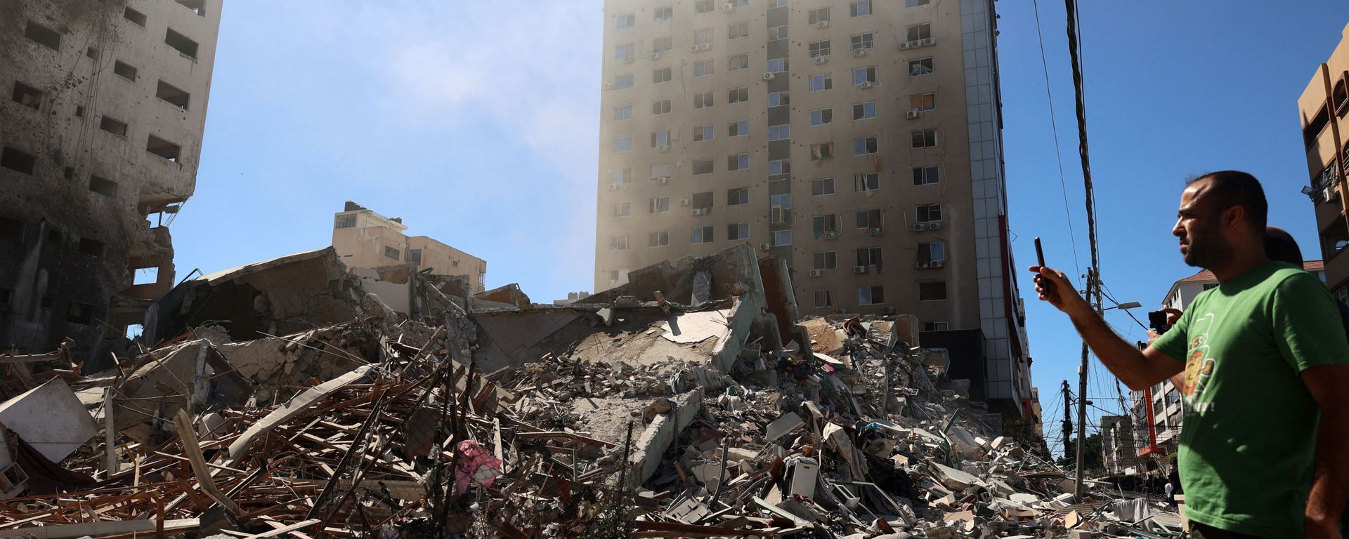 A Palestinian man takes a photograph with his mobile phone of a building hit and destroyed during an Israeli Air strike in Gaza City, on 15 May 2021. - Sputnik International, 1920, 16.05.2021
