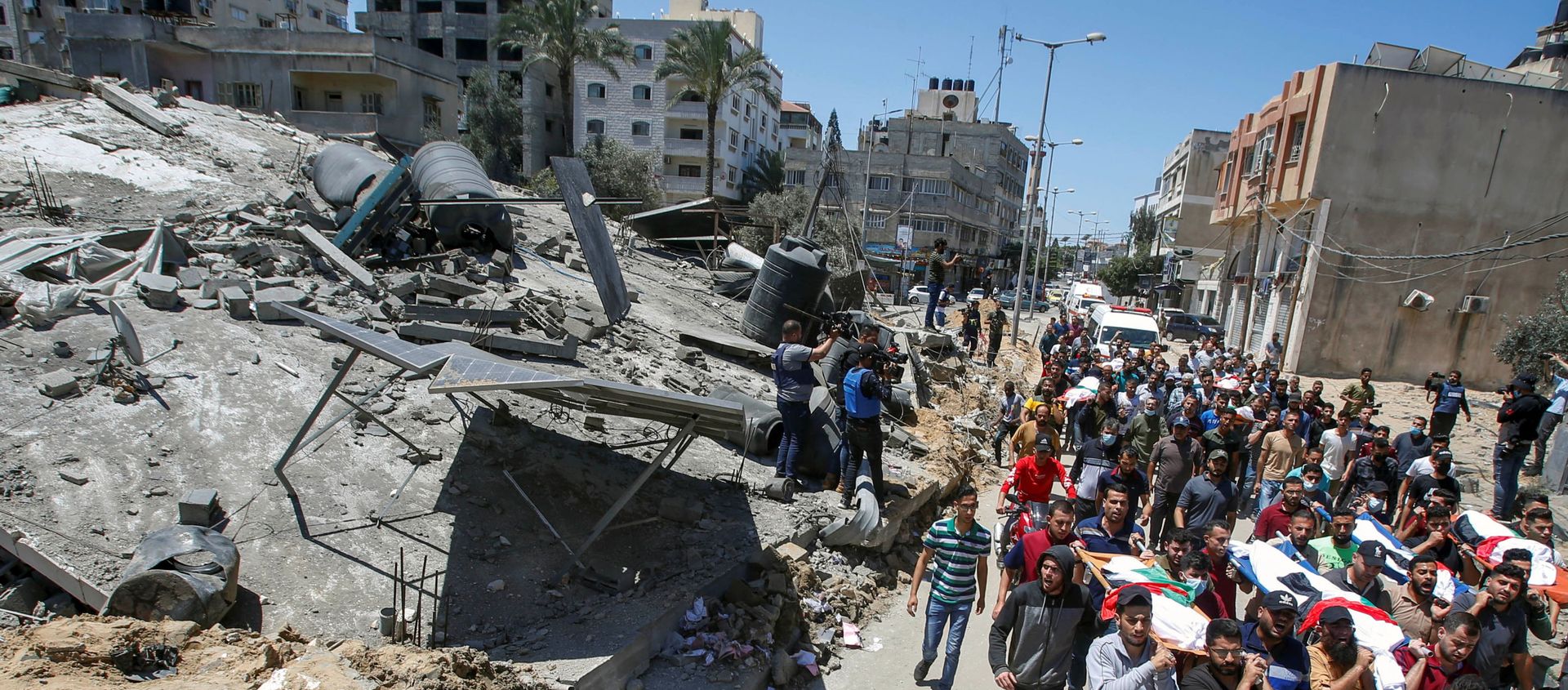 Mourners carry the bodies of Palestinians, including members of Abu Hatab family, who were killed amid a flare-up of Israeli-Palestinian violence, during their funeral near the remains of a building destroyed in Israeli air strikes, at the Beach refugee camp, in Gaza City May 15, 2021.  - Sputnik International, 1920, 16.05.2021