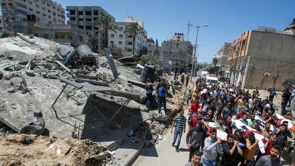Mourners carry the bodies of Palestinians, including members of Abu Hatab family, who were killed amid a flare-up of Israeli-Palestinian violence, during their funeral near the remains of a building destroyed in Israeli air strikes, at the Beach refugee camp, in Gaza City May 15, 2021.  - Sputnik International
