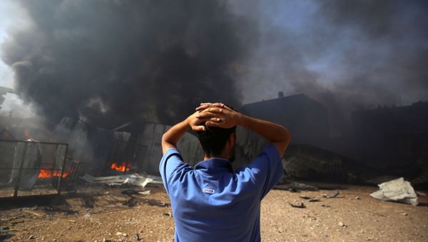 A man stands near a burning sponge factory after it was hit by Israeli artillery shells, according to witnesses, in the northern Gaza Strip May 17, 2021 - Sputnik International