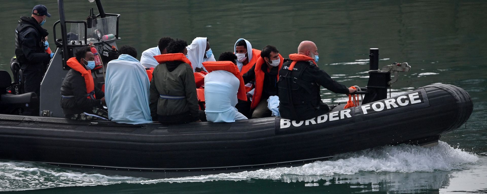 UK Border Force officials travel in a RIB with migrants picked up at sea whilst Crossing the English Channel, as they arrive at the Marina in Dover, southeast England on August 15, 2020 - Sputnik International, 1920, 16.04.2022