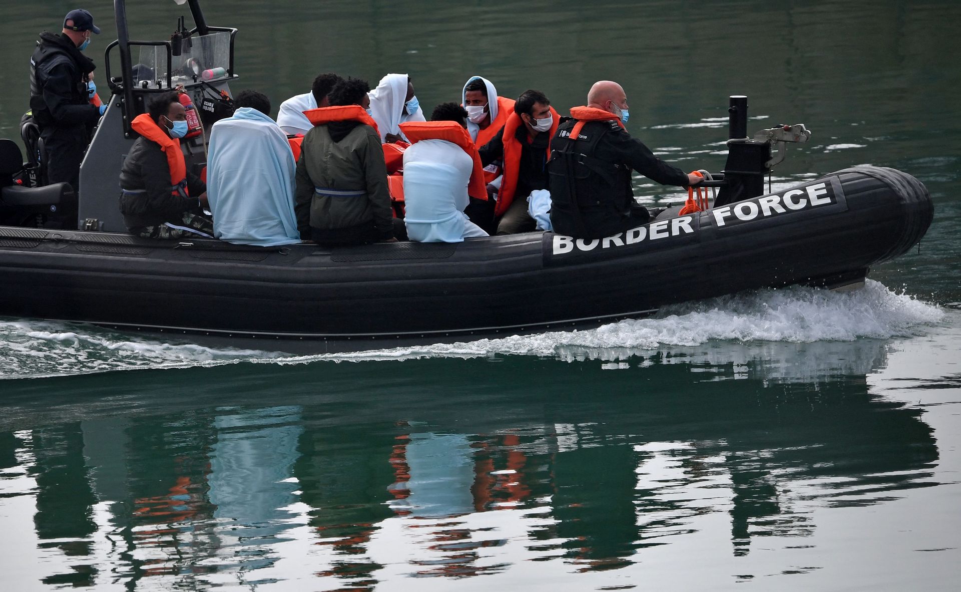 UK Border Force officials travel in a RIB with migrants picked up at sea whilst Crossing the English Channel, as they arrive at the Marina in Dover, southeast England on August 15, 2020 - Sputnik International, 1920, 04.11.2021