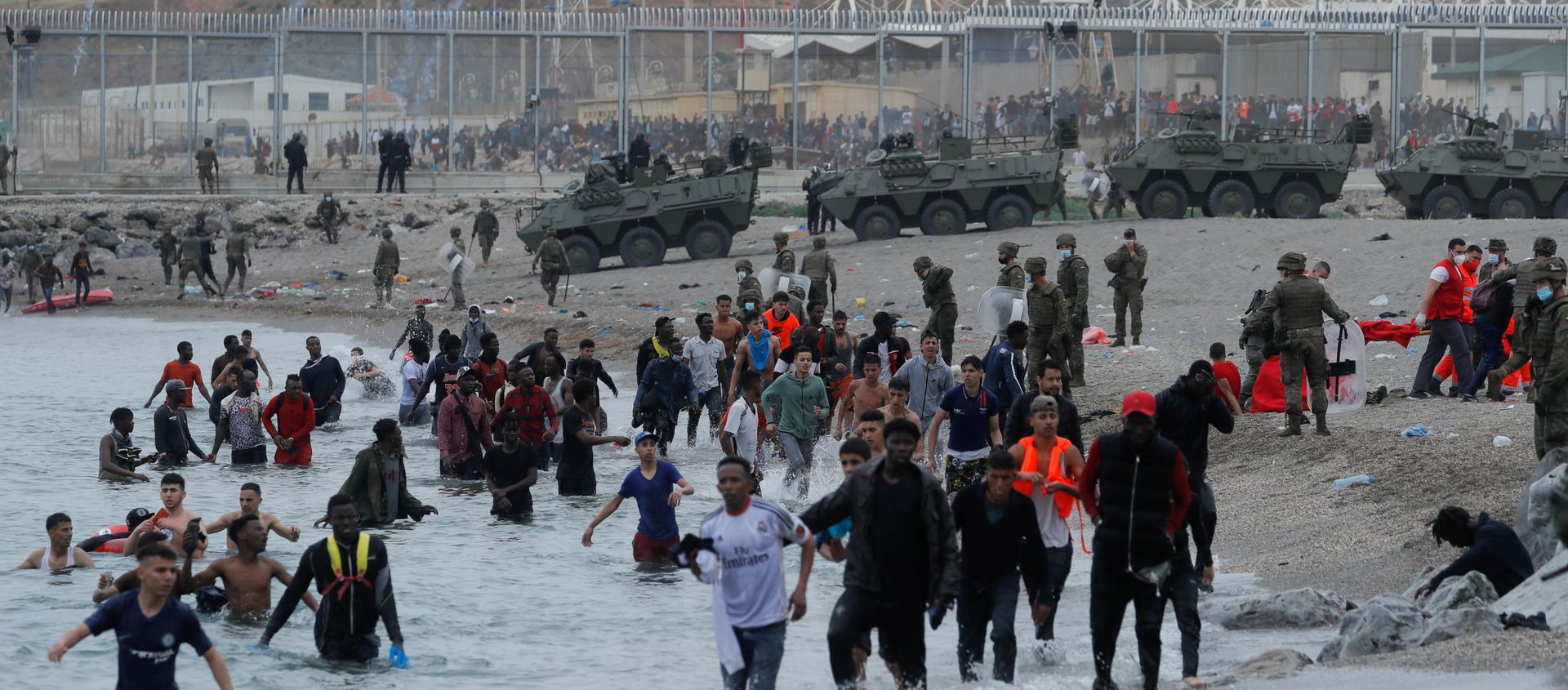 Moroccan citizens walk in the water as Spanish legionnaires patrol the area near the fence on a beach in El Tarajal, after thousands swam across the Spanish-Moroccan border on Monday, in Ceuta, Spain, May 18, 2021. REUTERS/Jon Nazca Moroccan citizens walk in the water as Spanish legionnaires patrol the area near the fence on a beach in El Tarajal, after thousands swam across the Spanish-Moroccan border on Monday, in Ceuta, Spain, May 18, 2021. REUTERS/Jon Nazca - Sputnik International, 1920, 18.05.2021