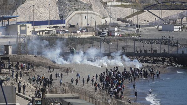 Spanish security forces throw tear gas at migrants attempting to cross the fence of the Spanish enclave of Ceuta - Sputnik International
