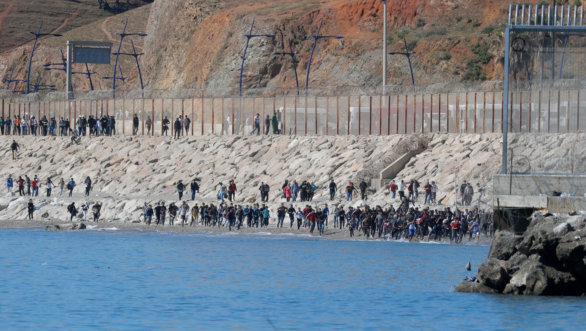 Migrants run towards the fence separating Morocco from Spain, after thousands of migrants swam across the border, in Ceuta, Spain, May 19, 2021. REUTERS/Jon Nazca Migrants run towards the fence separating Morocco from Spain, after thousands of migrants swam across the border, in Ceuta, Spain, May 19, 2021. REUTERS/Jon Nazca - Sputnik International, 1920, 20.05.2021