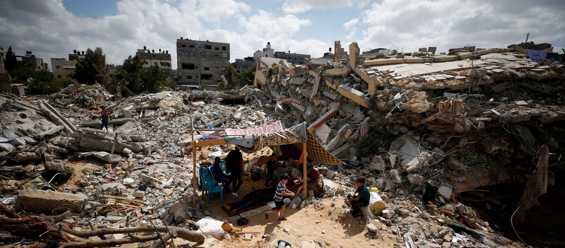 Palestinians sit in a makeshift tent amid the rubble of their houses, which were destroyed by Israeli air strikes during the Israel-Hamas fighting in Gaza, 23 May 2021. REUTERS/Mohammed Salem TPX IMAGES OF THE DAY Palestinians sit in a makeshift tent amid the rubble of their houses, which were destroyed by Israeli air strikes during the Israel-Hamas fighting in Gaza, 23 May 2021. REUTERS/Mohammed Salem TPX IMAGES OF THE DAY - Sputnik International, 1920, 24.05.2021