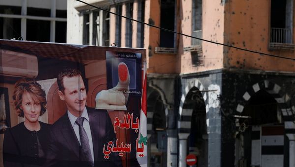 A view shows a banner depicting Syria's President Bashar al-Assad and his wife Asma, near a damaged building, ahead of the May 26 presidential election, in Homs, Syria May 23, 2021. - Sputnik International