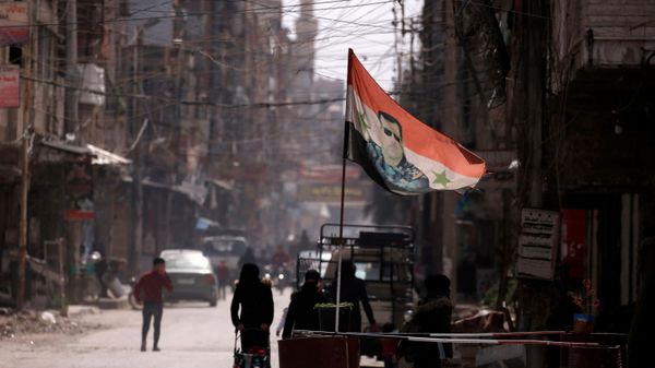 A national flag depicting a picture of Syria's President Bashar al-Assad flutters at a checkpoint in Douma, in the eastern suburbs of Damascus, Syria March 10, 2021. Picture taken March 10, 2021. - Sputnik International