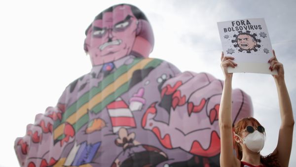 A demonstrator holds a banner reading Bolsonaro virus out during a protest against Brazil's President Jair Bolsonaro in Brasilia, Brazil, May 29, 2021. - Sputnik International