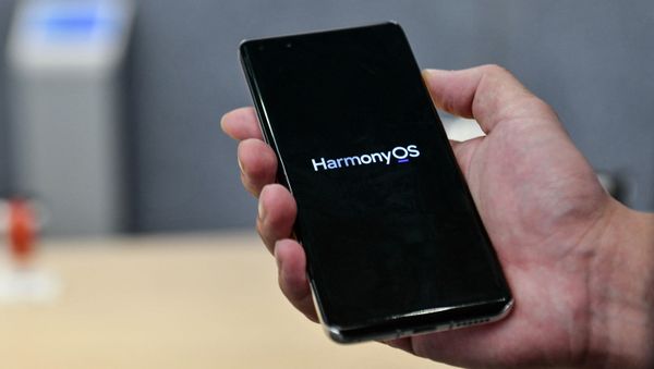 This photo taken on May 31, 2021 shows a staff member displaying a Huawei smartphone with the HarmonyOS operating system at the Huawei flagship store in Shenzhen, in China's southern Guangdong province. - Sputnik International