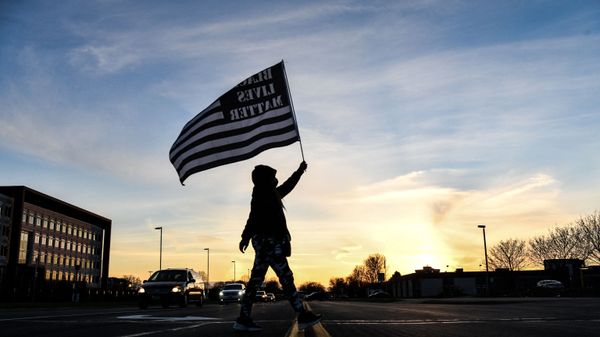 A demonstrator marches, holding a Black Lives Matter flag, during the sixth night of protests over the shooting death of Daunte Wright by a police officer in Brooklyn Center, Minnesota on April 16, 2021 - Sputnik International
