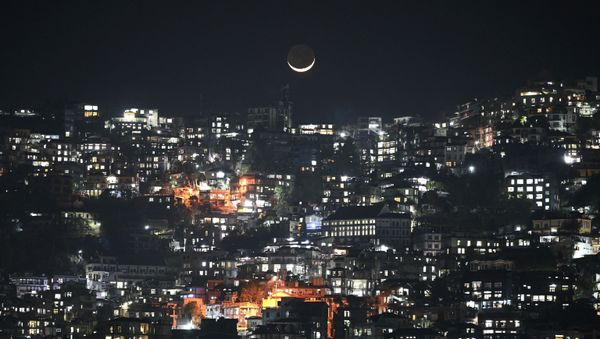 A general view shows a crescent moon over homes on a hillside in Aizawl, the capital of the northeastern Indian state of Mizoram on March 16, 2021 - Sputnik International