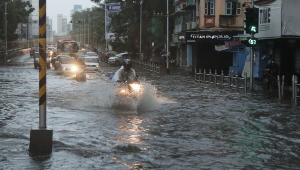 Commuters wade through a waterlogged street during a heavy rain in Mumbai, India, Monday, 17 May 2021 - Sputnik International