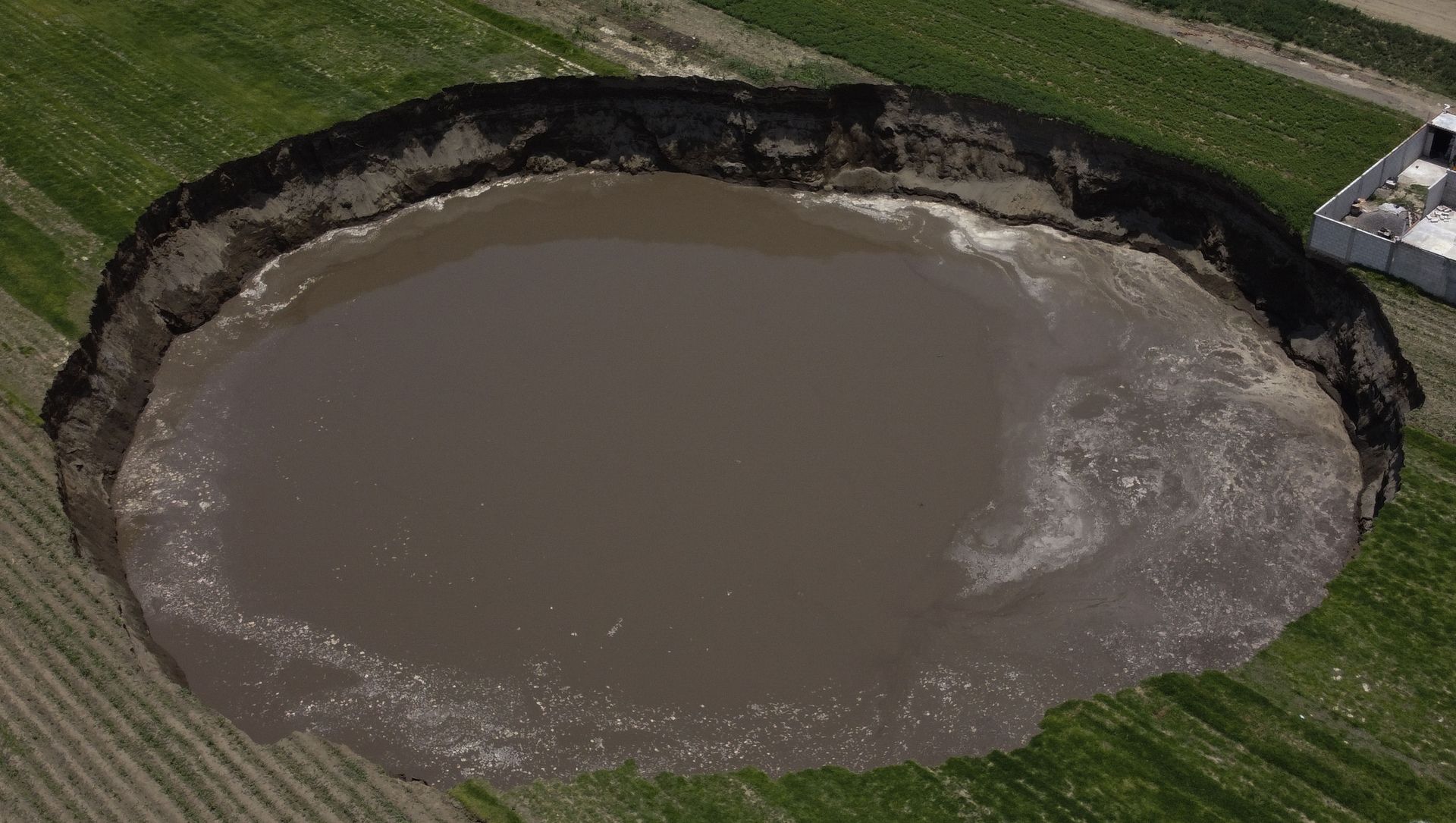 A water filled sinkhole grows in Zacatapec, on the outskirts of Puebla, Mexico, Tuesday, June 1, 2021. The massive water-filled sinkhole continues swallowing farmers' fields in the central Mexican state of Puebla. A water filled sinkhole grows in Zacatapec, on the outskirts of Puebla, Mexico, Tuesday, June 1, 2021. The massive water-filled sinkhole continues swallowing farmers' fields in the central Mexican state of Puebla. - Sputnik International, 1920, 15.06.2021