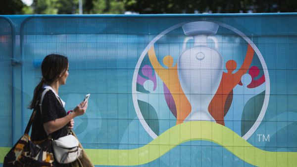 A pedestrian walks past the logo of the UEFA EURO 2020 European Football Championship in Copenhagen, one of the tournament's host cities, on June 10, 2021 - Sputnik International