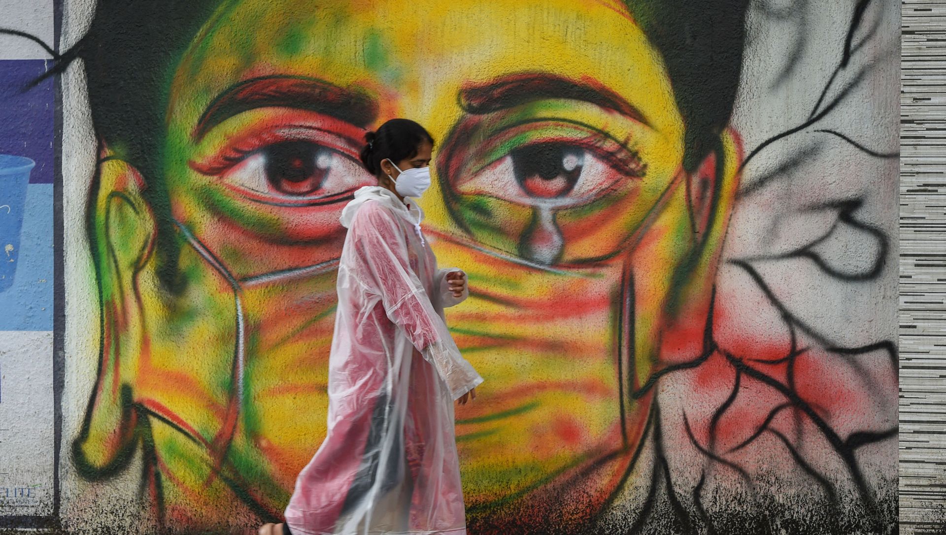 A woman wearing a raincoat walks past a mural depicting a woman with a facemask to spread awareness about the Covid-19 coronavirus, in Mumbai on June 17, 2021 A woman wearing a raincoat walks past a mural depicting a woman with a facemask to spread awareness about the Covid-19 coronavirus, in Mumbai on June 17, 2021 - Sputnik International, 1920, 17.06.2021