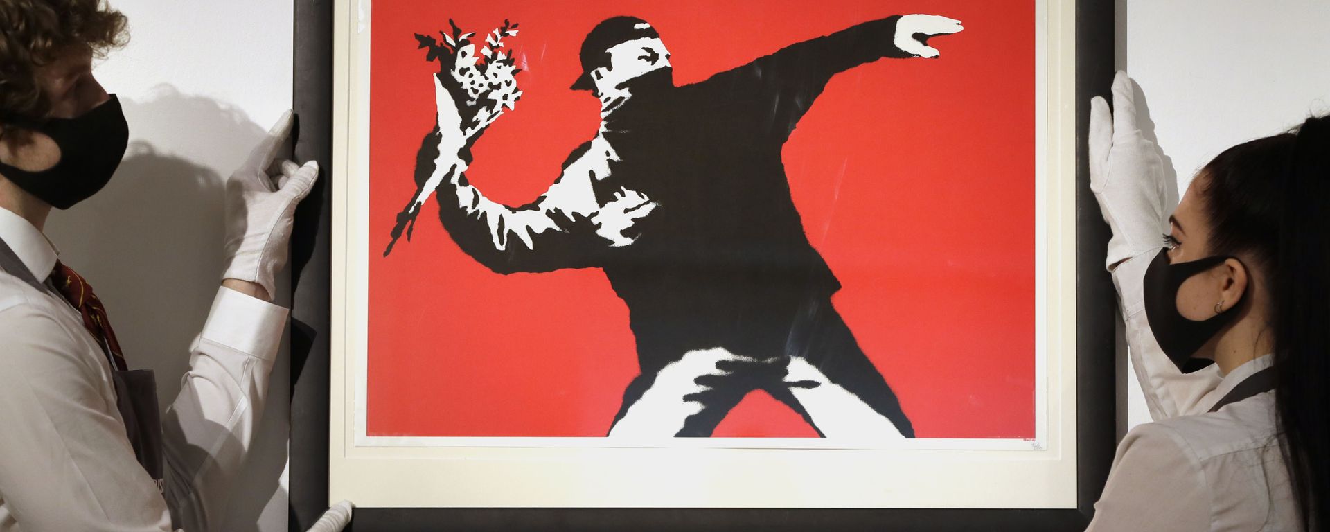 Gallery technicians display a Banksy called Love is in the Air screenprint in colours, 2003, on wove paper, numbered 412/500 in pencil at Christie's auction rooms in London, Friday, March 26, 2021 Gallery technicians display a Banksy called Love is in the Air screenprint in colours, 2003, on wove paper, numbered 412/500 in pencil at Christie's auction rooms in London, Friday, March 26, 2021 - Sputnik International, 1920, 03.10.2023