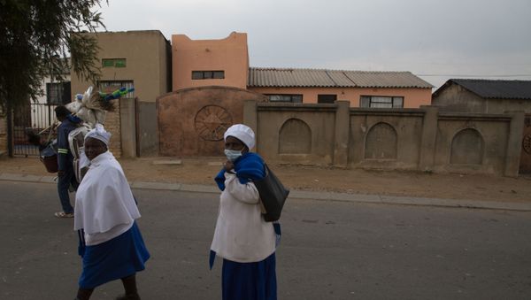 Neighbourhood woman passes the home, background, of Gosiame Thamara Sithole in Tembisa, near Johannesburg, Thursday, June 10, 2021. South Africa is gripped by a mystery over if the woman, Sithole, has, as has been claimed, given birth to 10 babies in what would be a world-first case of decuplets.  The South African government said Thursday it is still trying to verify the claim. - Sputnik International