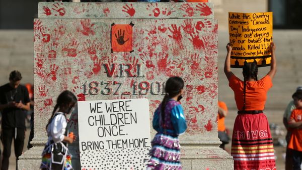 Young dancers circle a statue of Queen Victoria, toppled during a rally, following the discovery of the remains of hundreds of children at former indigenous residential schools, outside the provincial legislature on Canada Day in Winnipeg, Manitoba, Canada, 1 July 2021.   - Sputnik International