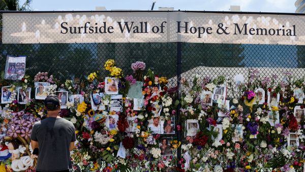 A man mourns at the memorial for victims of a partially collapsed residential building as the emergency crews continue the search and rescue operations for survivors, in Surfside, near Miami Beach, Florida, U.S. July 2, 2021 - Sputnik International