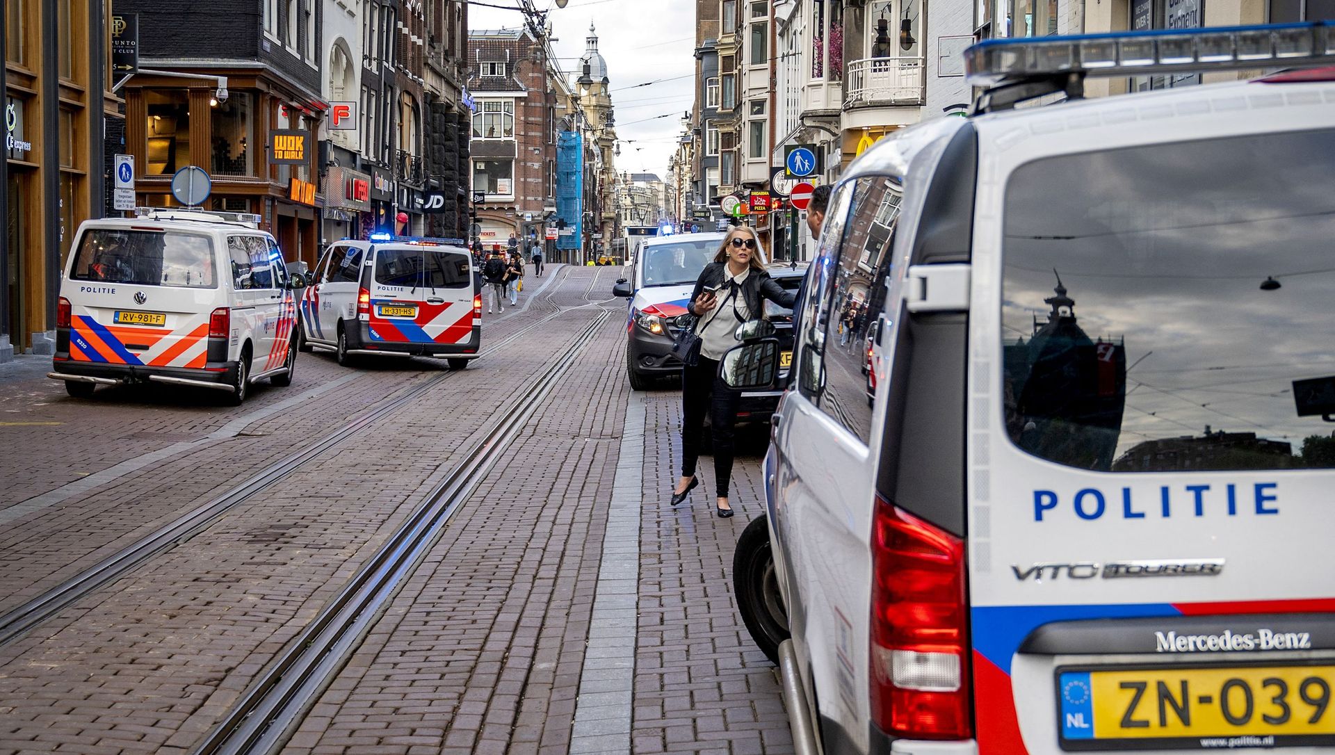 A woman walks past police vehicles parked on the site of an attack during which a Dutch journalist specialised in crime, Peter R. de Vries was seriously injured in a shooting in Amsterdam, on July 6, 2021. A woman walks past police vehicles parked on the site of an attack during which a Dutch journalist specialised in crime, Peter R. de Vries was seriously injured in a shooting in Amsterdam, on July 6, 2021. - Sputnik International, 1920, 06.07.2021