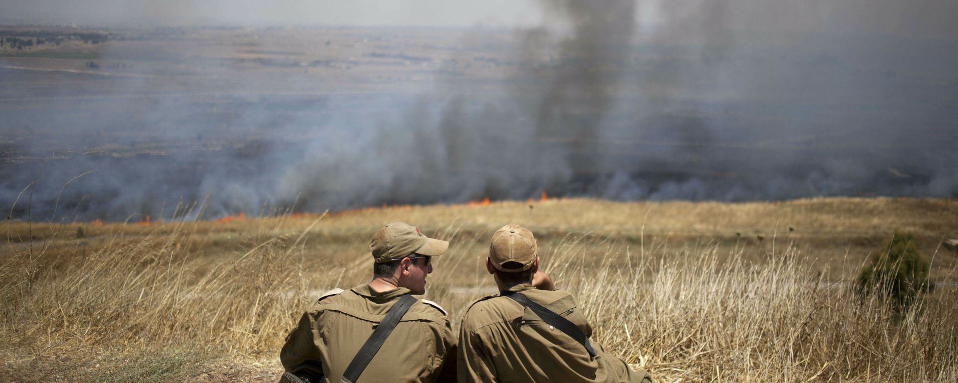 FILE - In this July 16, 2013, file photo, Israeli soldiers sit in a position on the border with Syria on the Israeli-controlled Golan Heights as smoke rises following explosions of mortar shells - Sputnik International, 1920, 09.12.2024