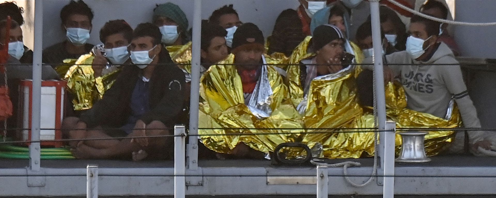 Migrants warmed by emergency blankets arrive on a boat of the Italian Guardia Di Finanza law enforcement agency on May 17, 2021 to disembark on the southern Italian Pelagie Island of Lampedusa. - More than 1,400 migrants arrived on the Italian island of Lampedusa at the weekend, sparking calls from far-right politicians for action to stem the flow, amid fresh moves by Italian authorities against the rescue boats who operate in the central Mediterranean. - Sputnik International, 1920, 14.09.2023