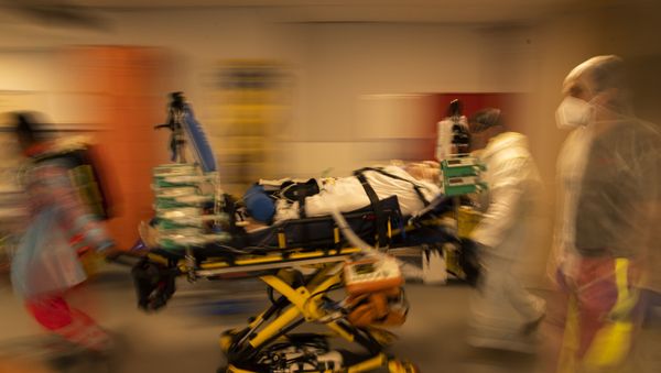 Medical personnel wearing protective equipment wheel a bed with a coronavirus patient in critical condition as they prepare to transfer the patient via ambulance to a hospital in Aachen, Germany, at the MontLegia CHC hospital in Liege, Belgium, 14 April 2021 - Sputnik International