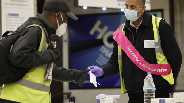 A London Underground worker, right, hands over a free face masks to a passenger at London's Baker Street station, Tuesday, June 9, 2020. Wearing a face mask will become compulsory on the London TFL public transport service starting from June 15, 2020, as a safety measure to contrast the COVID-19 pandemic.  - Sputnik International