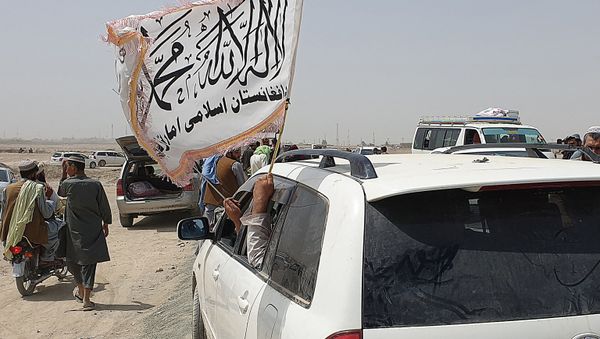 People wave a Taliban flag as they drive through the Pakistani border town of Chaman on July 14, 2021, after the Taliban claimed they had captured the Afghan side of the border crossing of Spin Boldak along the frontier with Pakistan - Sputnik International