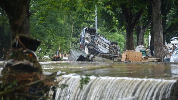 A car stands upside down near floating water in Iversheim, near Bad Muenstereifel, western Germany, on July 16, 2021, following heavy rains and floods. - The death toll from devastating floods in Europe soared to at least 126 on July 16, most in western Germany where emergency responders were frantically searching for missing people. - Sputnik International