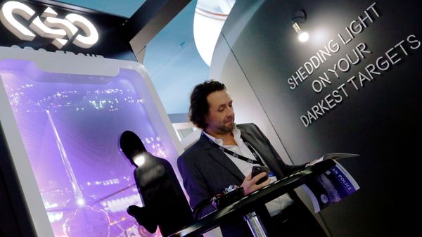 A man reads at a stand of the NSO Group Technologies, an Israeli technology firm known for its Pegasus spyware enabling the remote surveillance of smartphones, at the annual European Police Congress in Berlin, Germany, February 4, 2020. - Sputnik International