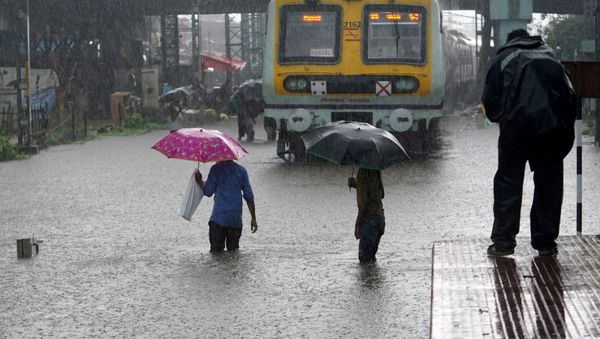 People cross inundated railway tracks next to a parked passenger train during heavy monsoon rains in Mumbai, India, June 9, 2021 - Sputnik International