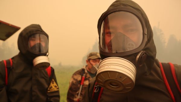 Firefighters wear protective clothing while working to extinguish a forest fire near the village of Magaras in the region of Yakutia, Russia July 17, 2021.  - Sputnik International