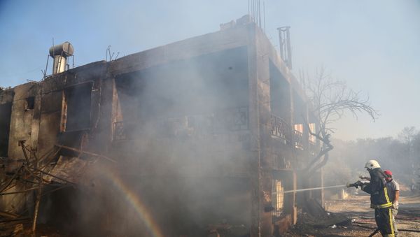 A firefighter cools a burnt house as a massive forest fire spread to the town of Manavgat, 75 km (45 miles) east of the resort city of Antalya, Turkey, on 28 July 2021. - Sputnik International