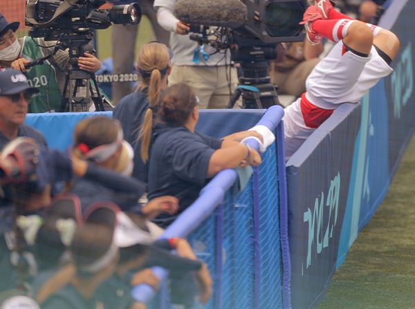 Japan's third baseman Yu Yamamoto (R top) falls into the photographer's area as she chases a fly ball during the sixth inning of the opening round game between Japan and the US. - Sputnik International