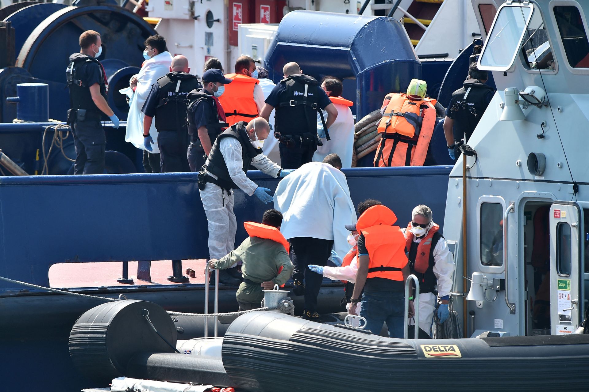 UK Border Force officers help migrants, believed to have been picked up from boats in the Channel, disembark from Coastal patrol vessel HMC Speedwell, in the port of Dover, on the south-east coast of England on August 9, 2020. - The British government on Sunday appointed a former marine to lead efforts to tackle illegal migration in the Channel ahead of talks with France on how to stop the dangerous crossings. (Photo by Glyn KIRK / AFP) - Sputnik International, 1920, 23.11.2021
