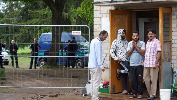 Migrants stand near a fence at a temporary detention center in Kazitiskis, Lithuania, August 12, 2021. Picture taken on August 12, 2021.  - Sputnik International