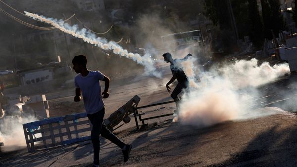 Palestinian protester throws back a tear gas grenade during a protest over the killing of a Palestinian man by Israeli soldiers, according to health ministry, in Beita in the Israeli-occupied West Bank July 28, 2021 - Sputnik International