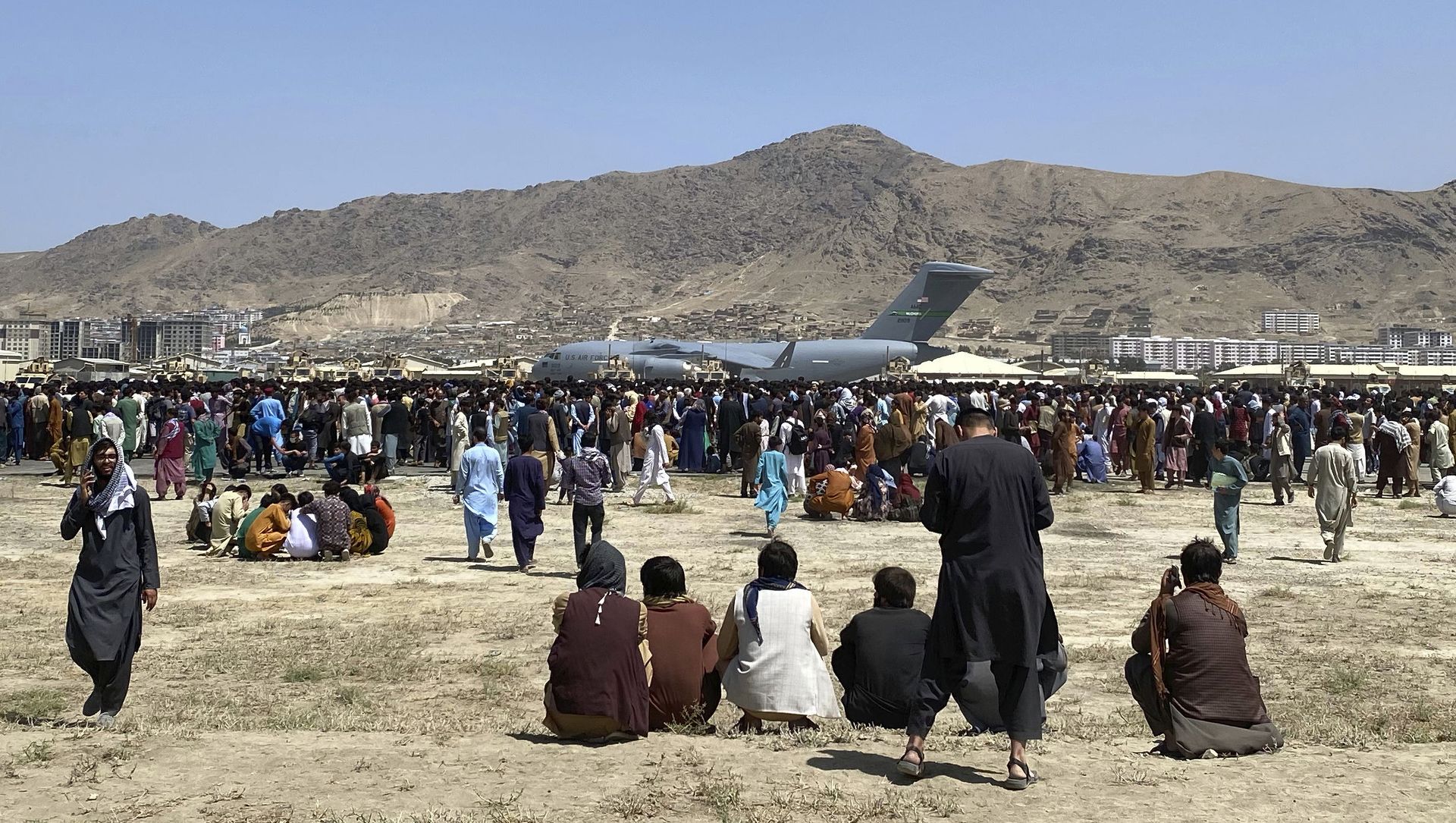 Hundreds of people gather near a U.S. Air Force C-17 transport plane at a perimeter at the international airport in Kabul, Afghanistan, Monday, Aug. 16, 2021. On Monday, the U.S. military and officials focus was on Kabul’s airport, where thousands of Afghans trapped by the sudden Taliban takeover rushed the tarmac and clung to U.S. military planes deployed to fly out staffers of the U.S. Embassy, which shut down Sunday, and others Hundreds of people gather near a U.S. Air Force C-17 transport plane at a perimeter at the international airport in Kabul, Afghanistan, Monday, Aug. 16, 2021. On Monday, the U.S. military and officials focus was on Kabul’s airport, where thousands of Afghans trapped by the sudden Taliban takeover rushed the tarmac and clung to U.S. military planes deployed to fly out staffers of the U.S. Embassy, which shut down Sunday, and others - Sputnik International, 1920, 17.08.2021